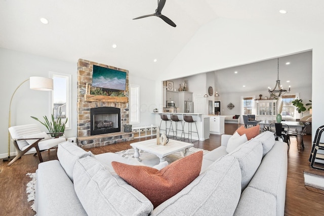 living room with hardwood / wood-style flooring, a fireplace, high vaulted ceiling, and ceiling fan with notable chandelier