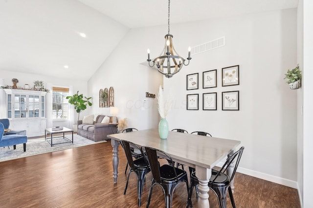 dining area featuring vaulted ceiling, hardwood / wood-style floors, and an inviting chandelier