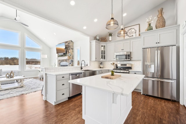 kitchen with sink, tasteful backsplash, appliances with stainless steel finishes, a kitchen island, and pendant lighting