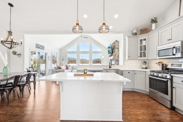 kitchen featuring lofted ceiling, appliances with stainless steel finishes, sink, and hanging light fixtures