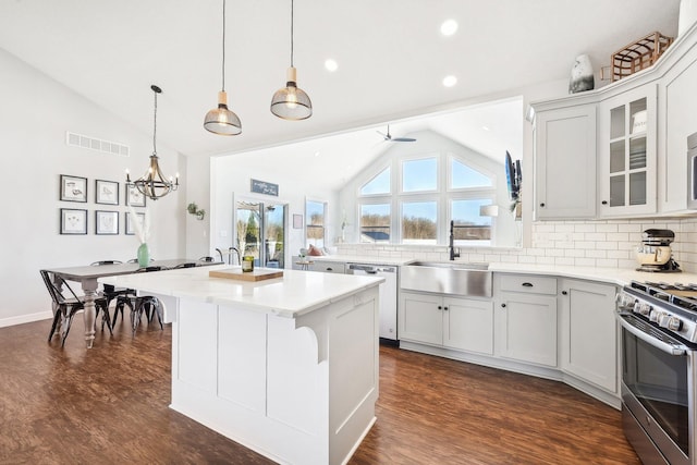 kitchen with stainless steel appliances, a kitchen island, lofted ceiling, and sink