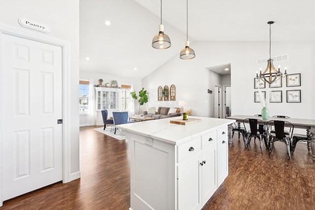 kitchen with dark wood-type flooring, white cabinets, light stone counters, and decorative light fixtures