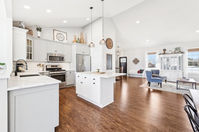 kitchen featuring sink, appliances with stainless steel finishes, a center island, tasteful backsplash, and decorative light fixtures