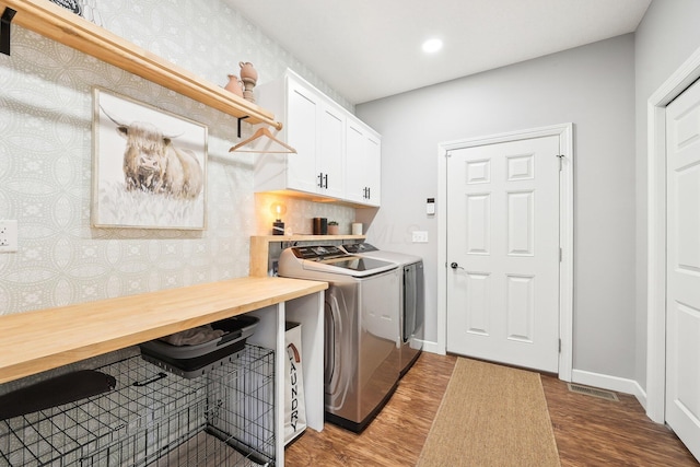 washroom featuring cabinets, wood-type flooring, and washing machine and dryer