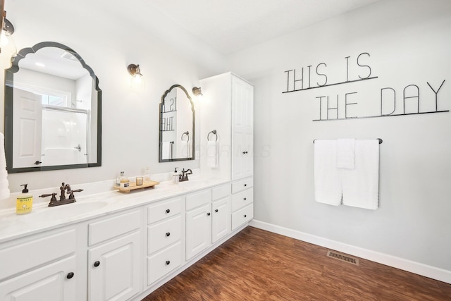 bathroom featuring hardwood / wood-style flooring, vanity, and a shower with door