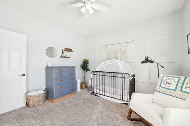 carpeted bedroom with a nursery area and ceiling fan