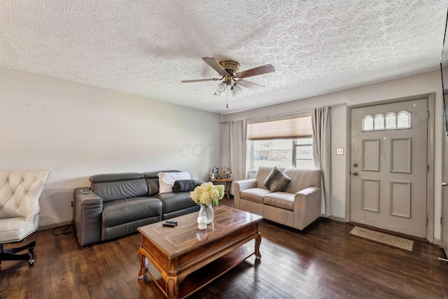 living room with a textured ceiling, dark wood-type flooring, and ceiling fan