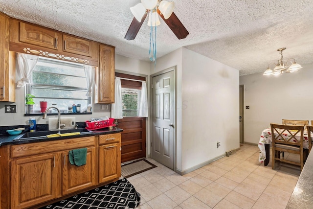 kitchen with a textured ceiling, ceiling fan with notable chandelier, plenty of natural light, and sink