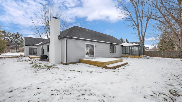 snow covered back of property with a sunroom