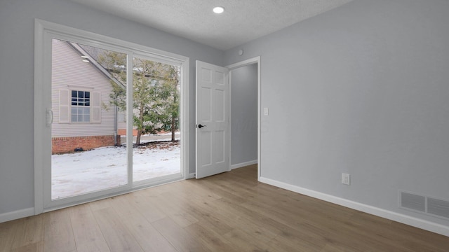 interior space with a textured ceiling and light hardwood / wood-style flooring