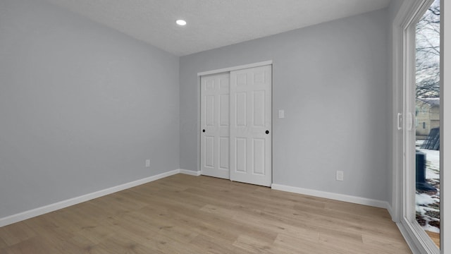 unfurnished bedroom featuring a closet, a textured ceiling, and light hardwood / wood-style floors