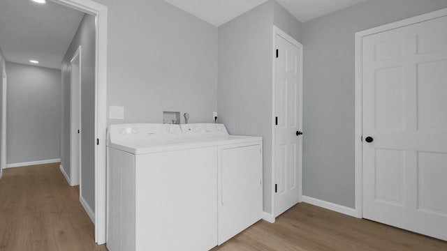 clothes washing area with light wood-type flooring and separate washer and dryer