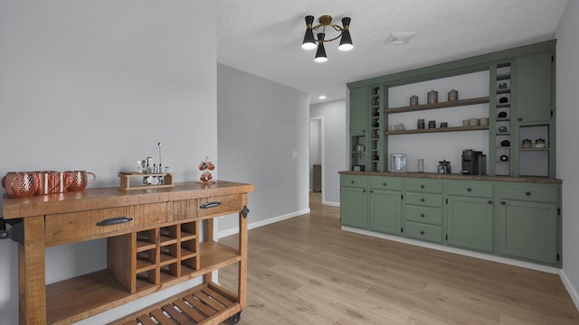 bar with green cabinets, a textured ceiling, and light hardwood / wood-style floors