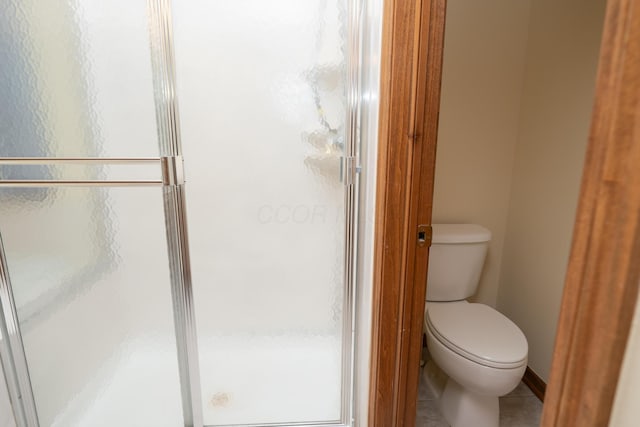 bathroom featuring toilet, a stall shower, and tile patterned floors