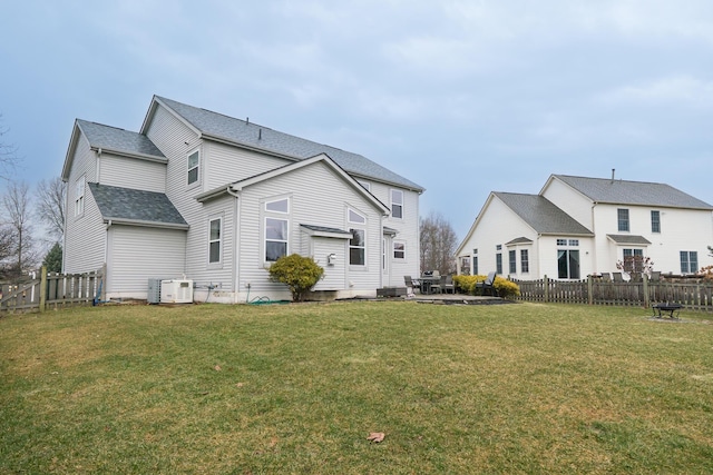 rear view of property featuring a lawn, a patio, roof with shingles, fence, and cooling unit