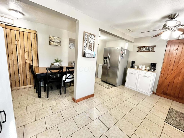 kitchen with stainless steel refrigerator with ice dispenser, ceiling fan, a textured ceiling, and white cabinets