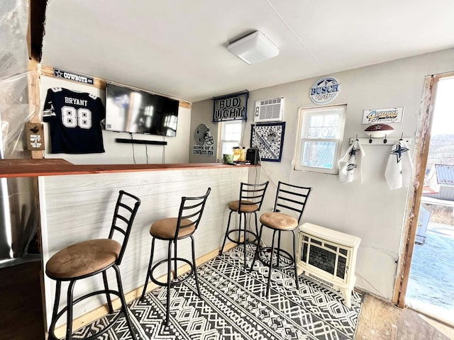 bar with heating unit, a wall mounted AC, and hardwood / wood-style floors