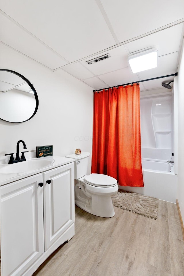 full bathroom featuring a paneled ceiling, vanity, wood-type flooring, toilet, and shower / bath combo with shower curtain