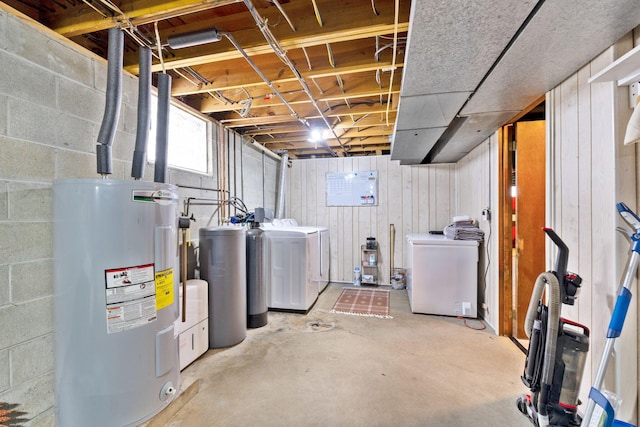 basement featuring washer and clothes dryer, water heater, and wooden walls