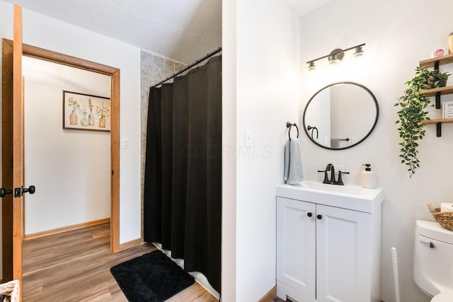 bathroom featuring hardwood / wood-style floors, vanity, a textured ceiling, toilet, and walk in shower