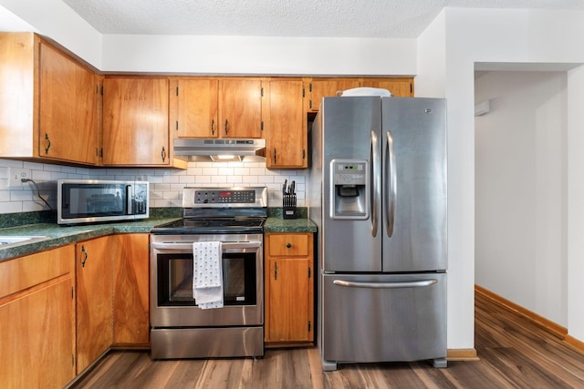 kitchen featuring tasteful backsplash, dark wood-type flooring, a textured ceiling, and appliances with stainless steel finishes