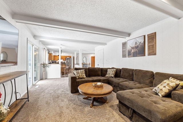 carpeted living room with beamed ceiling, wooden walls, and a textured ceiling