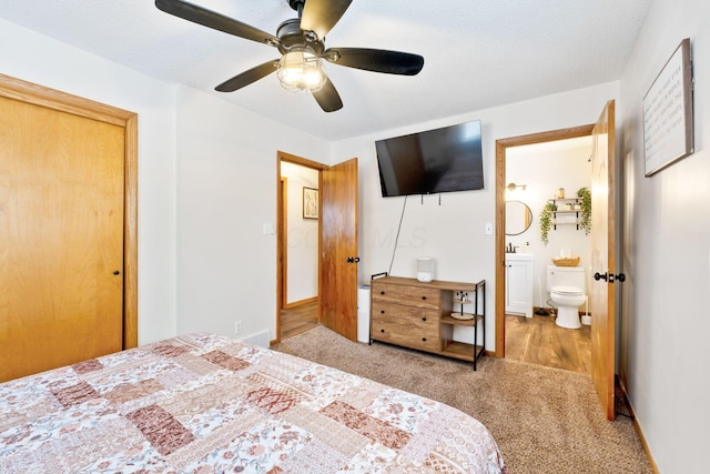 carpeted bedroom with ceiling fan, ensuite bath, and a textured ceiling