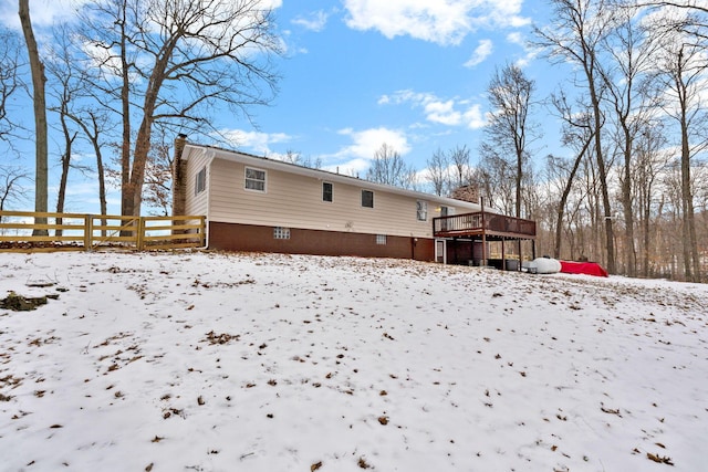 snow covered back of property with a wooden deck