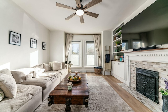 living room featuring ceiling fan, light hardwood / wood-style floors, and a tile fireplace