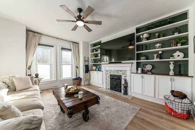 living room with light hardwood / wood-style flooring, built in features, and ceiling fan