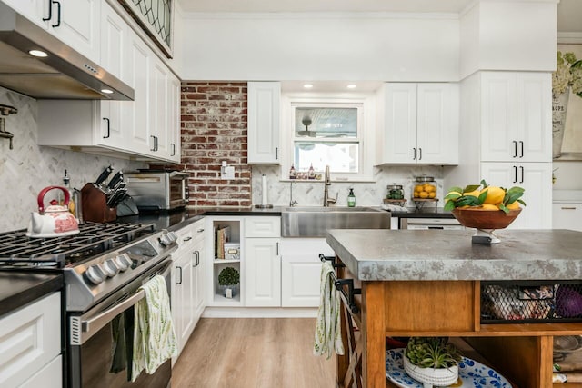 kitchen featuring white cabinetry, backsplash, sink, and stainless steel gas range oven