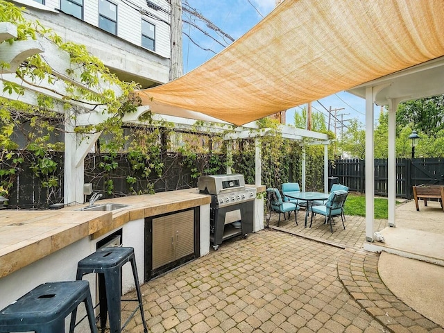 view of patio with area for grilling, a grill, a pergola, and a wet bar