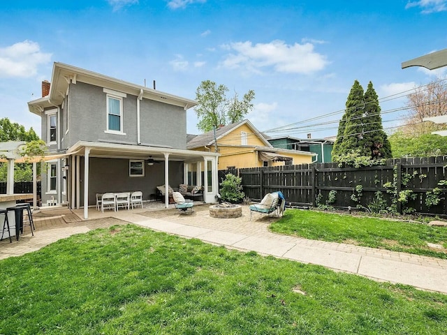 rear view of property with a yard, a fire pit, and a patio area