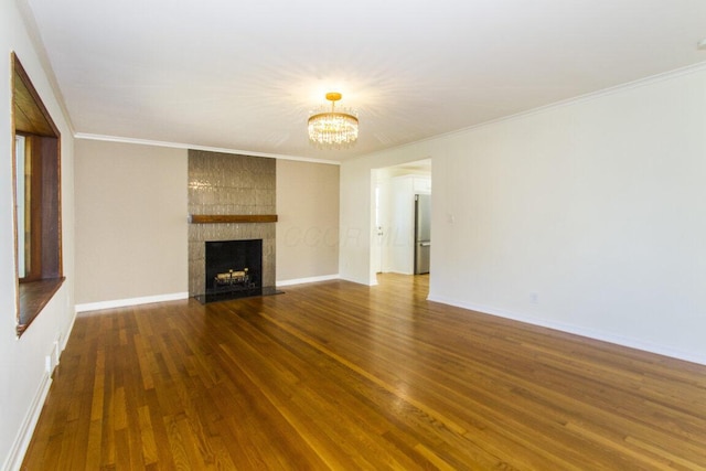 unfurnished living room with ornamental molding, a tile fireplace, and a notable chandelier