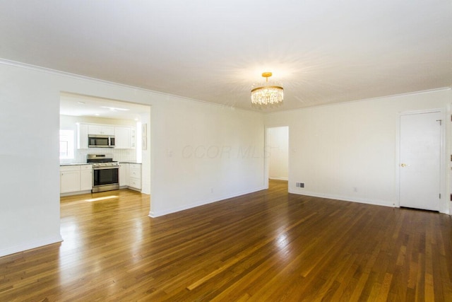 spare room featuring dark wood-type flooring, a chandelier, and ornamental molding