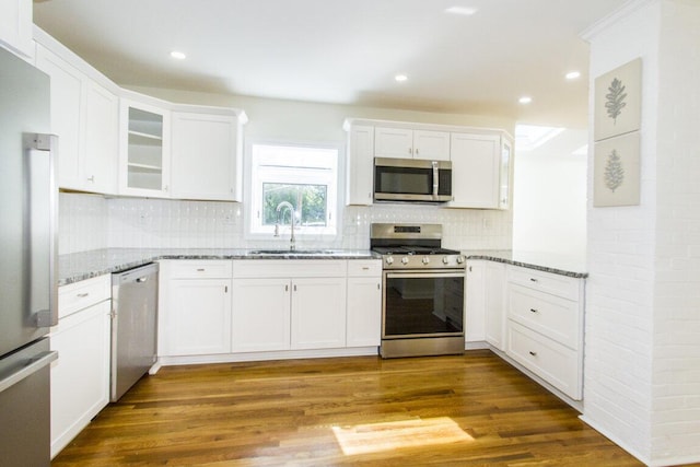 kitchen with stainless steel appliances, dark wood-type flooring, light stone countertops, white cabinets, and sink