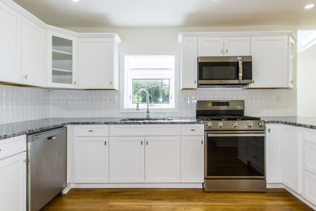 kitchen with sink, white cabinets, appliances with stainless steel finishes, and dark stone countertops