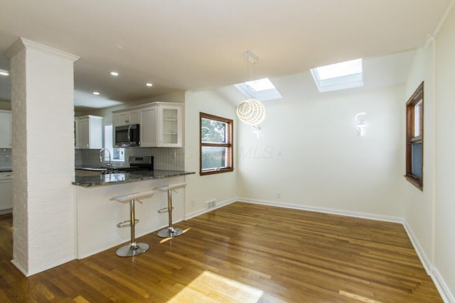 kitchen with a kitchen bar, kitchen peninsula, white cabinetry, and stainless steel appliances