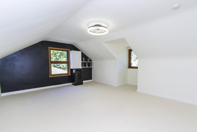 additional living space featuring light colored carpet, a wealth of natural light, and lofted ceiling