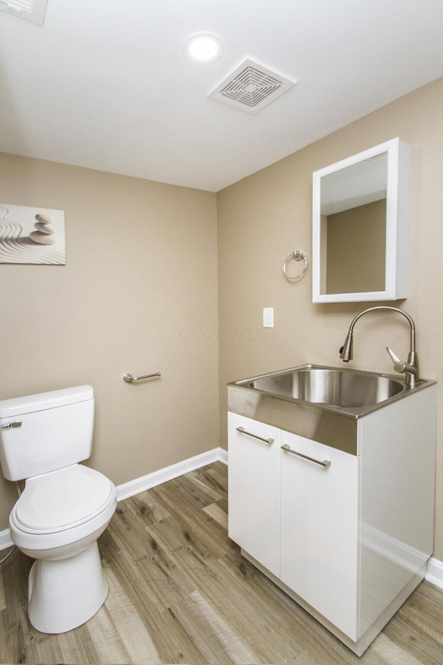 bathroom with toilet, vanity, and hardwood / wood-style floors