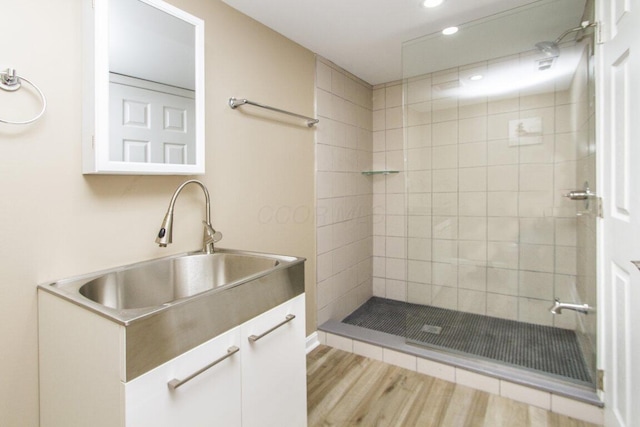 bathroom with vanity, hardwood / wood-style floors, and tiled shower