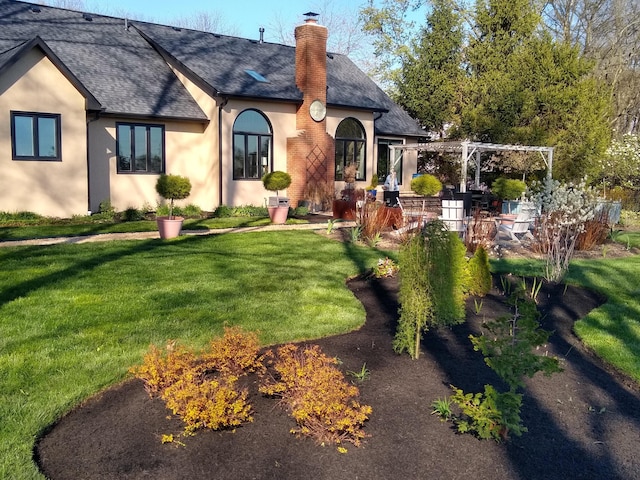 rear view of house with a yard and a pergola