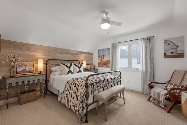 bedroom with vaulted ceiling, light colored carpet, ceiling fan, and wooden walls