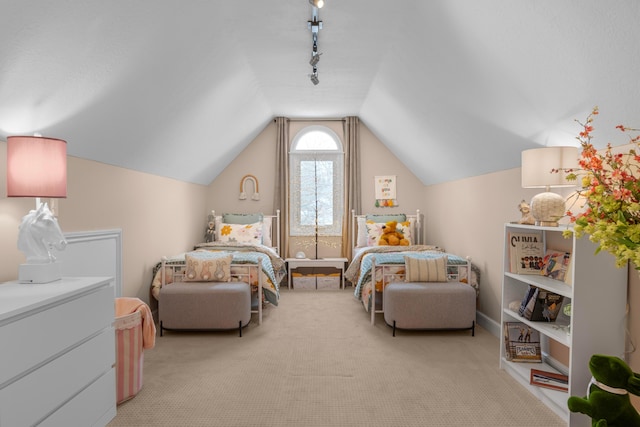 bedroom featuring lofted ceiling, track lighting, and light colored carpet