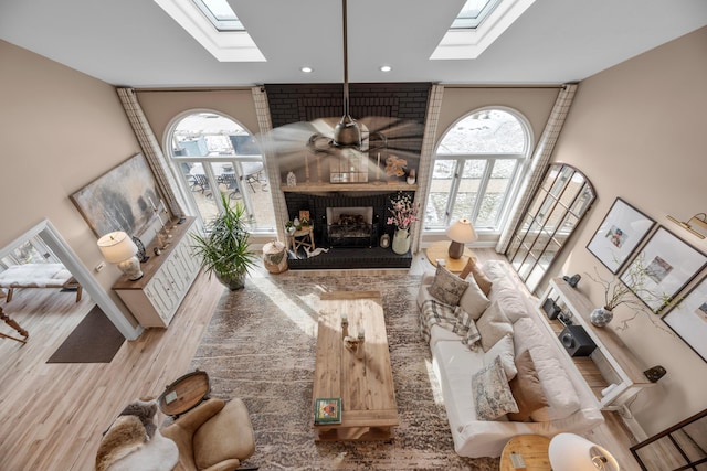 living room featuring hardwood / wood-style flooring, a fireplace, and a skylight