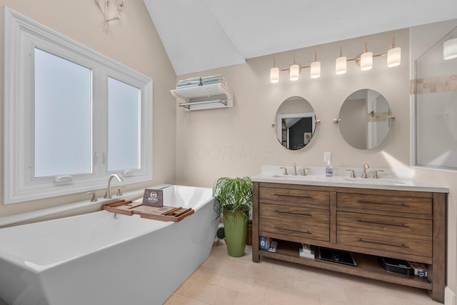 bathroom featuring tile patterned floors, a tub to relax in, vaulted ceiling, and vanity