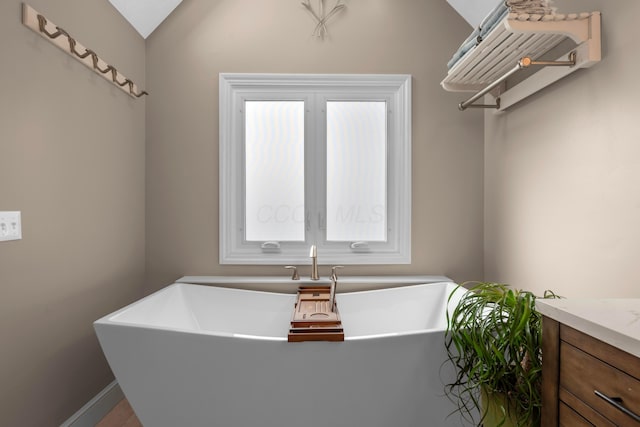 bathroom featuring lofted ceiling, vanity, and a washtub