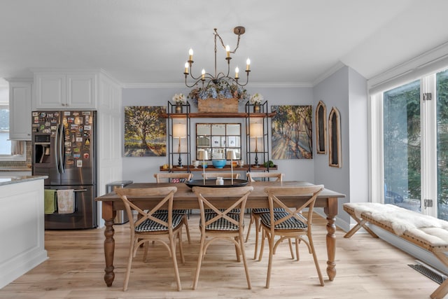 dining space with crown molding, a chandelier, and light wood-type flooring