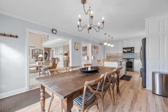 dining space with an inviting chandelier, sink, ornamental molding, and light hardwood / wood-style floors