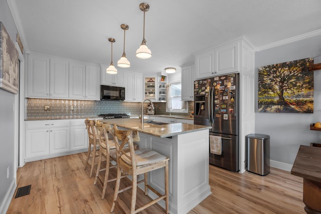 kitchen with white cabinetry, a kitchen island with sink, light stone countertops, and stainless steel refrigerator with ice dispenser